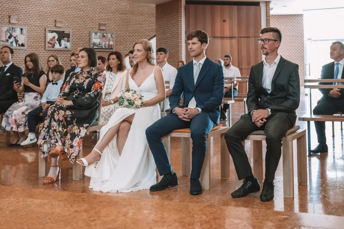 Poročna fotografija mladoporočencev; ujet pristen trenutek z naravno svetlobo in umirjeno kompozicijo v dokumentarnem slogu.